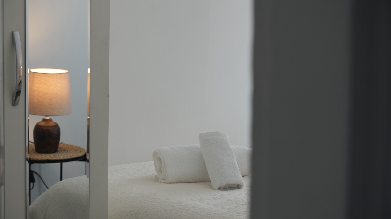 Rolled towels on a made bed reflected in a mirrored wardrobe, Coventry