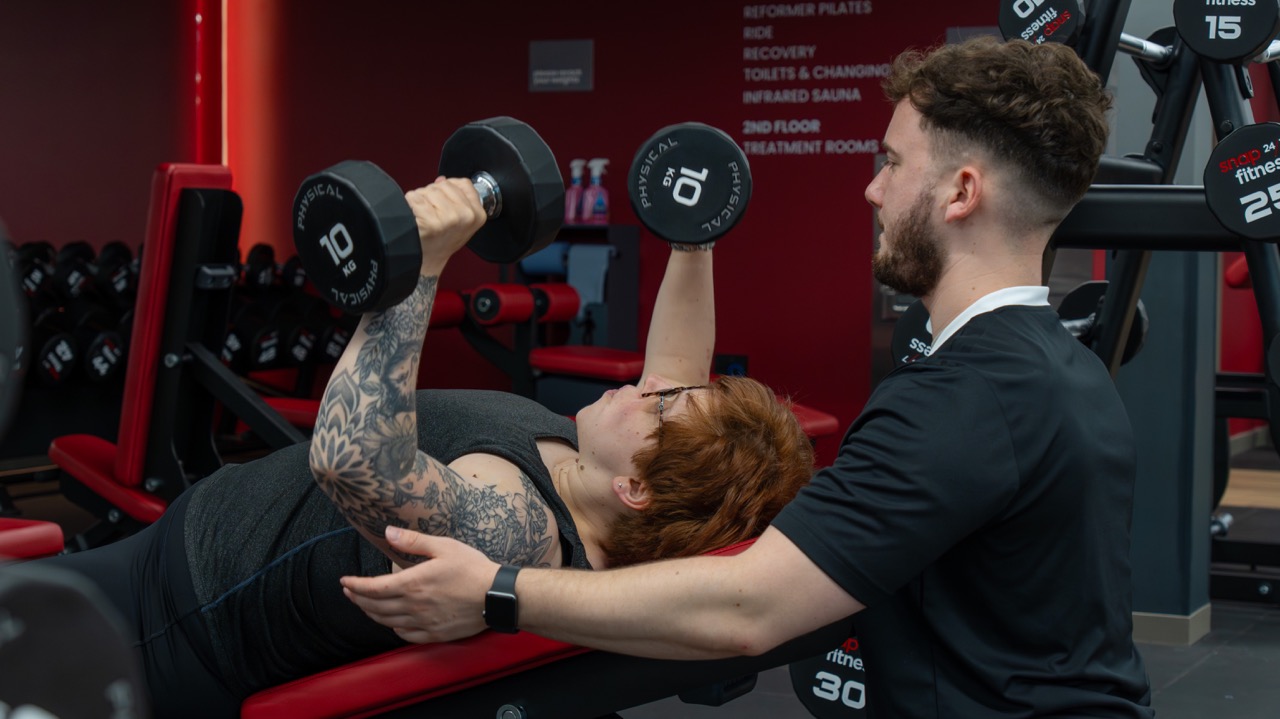 Trainer spotting a client on a dumbbell bench press