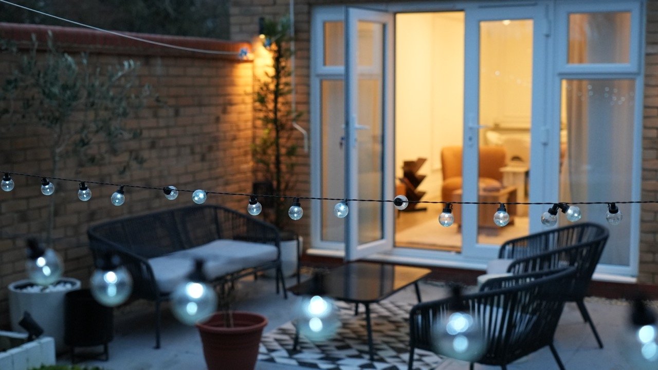 Courtyard garden with festoon lighting and seating at dusk, Milton Keynes