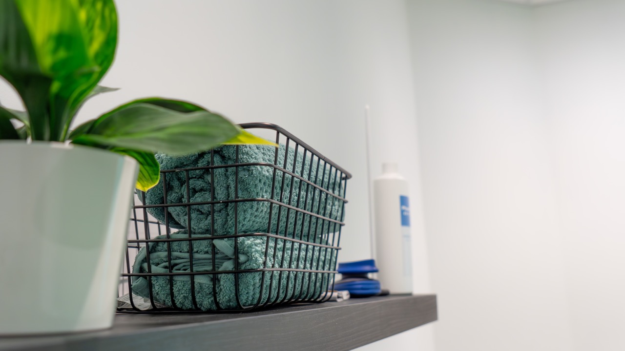 Folded clinic towels and plant detail on a shelf