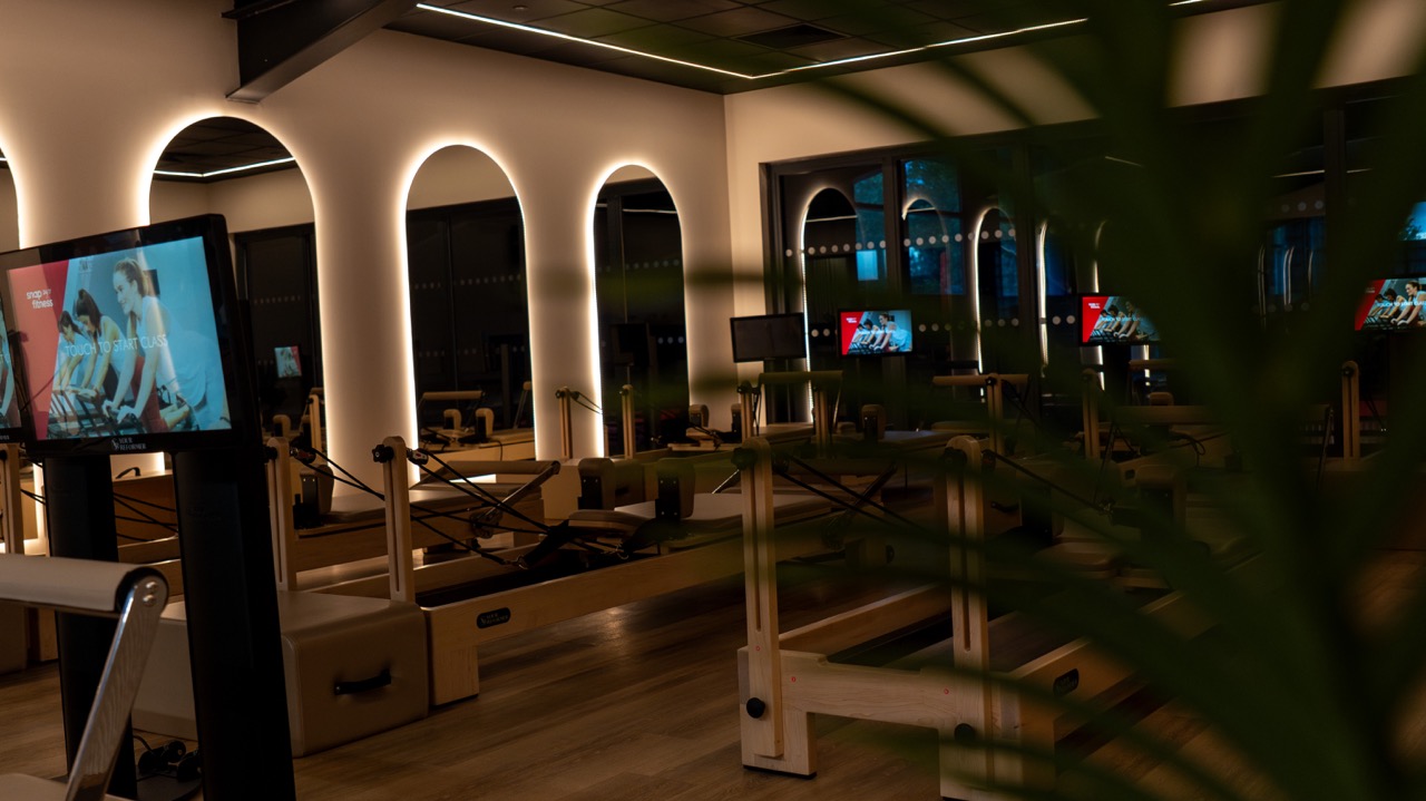 Reformer pilates studio with arched lighting and screens