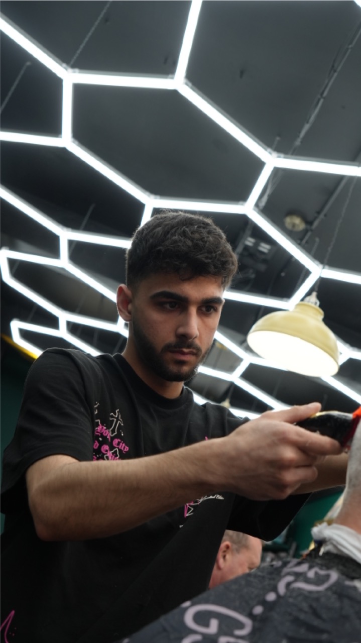 Barber lining up a fade under hexagon lighting at Rustington Barbers