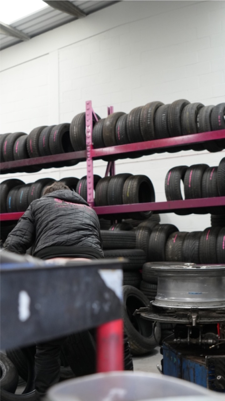 Fitter sorting through racked part-worn tyres in the workshop