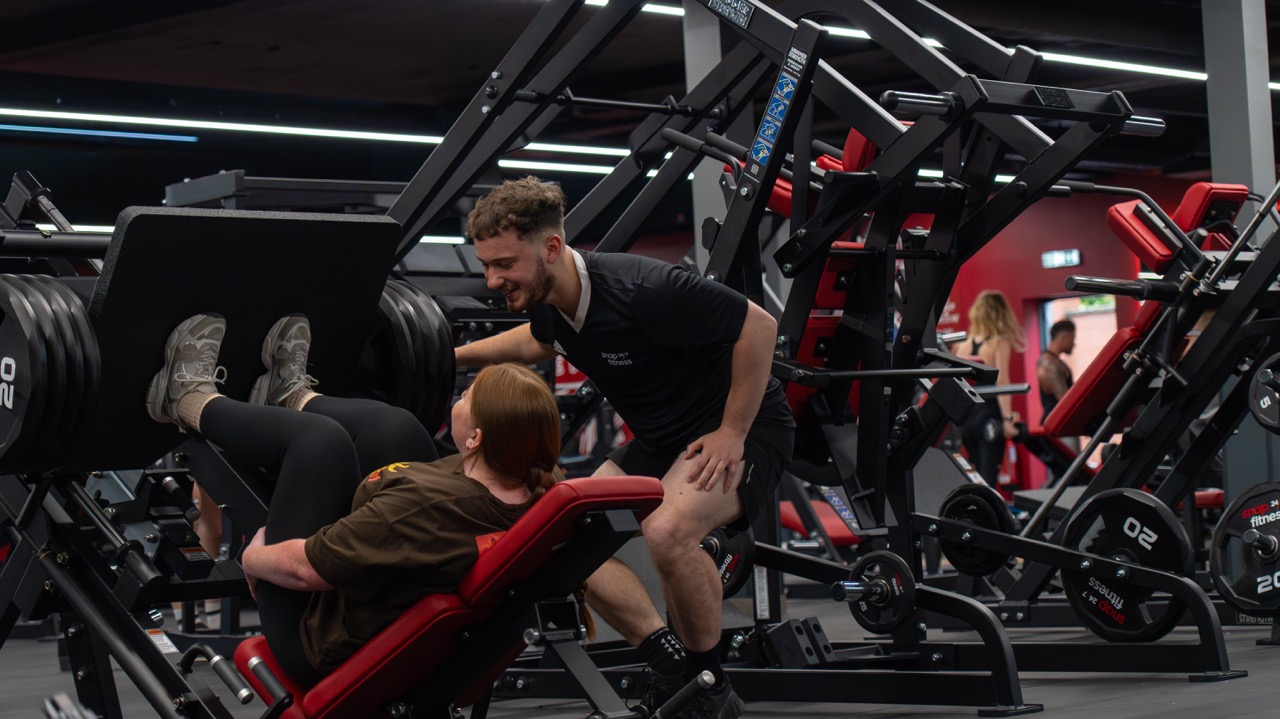 Personal trainer coaching a client through a leg press at ECPT
