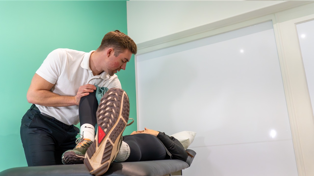 Physiotherapist treating a patient's leg on the plinth