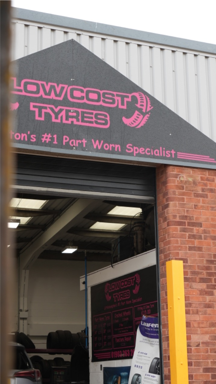 Low Cost Tyres unit and pink signage seen from the forecourt