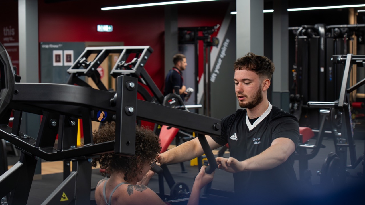 Trainer setting up a client on a chest press machine