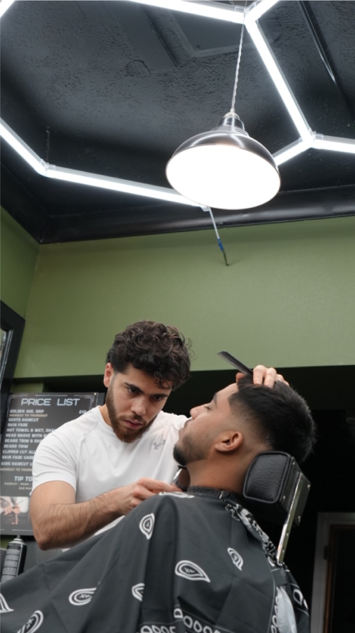 Beard and neckline detail under a pendant light at Tip Top Worthing