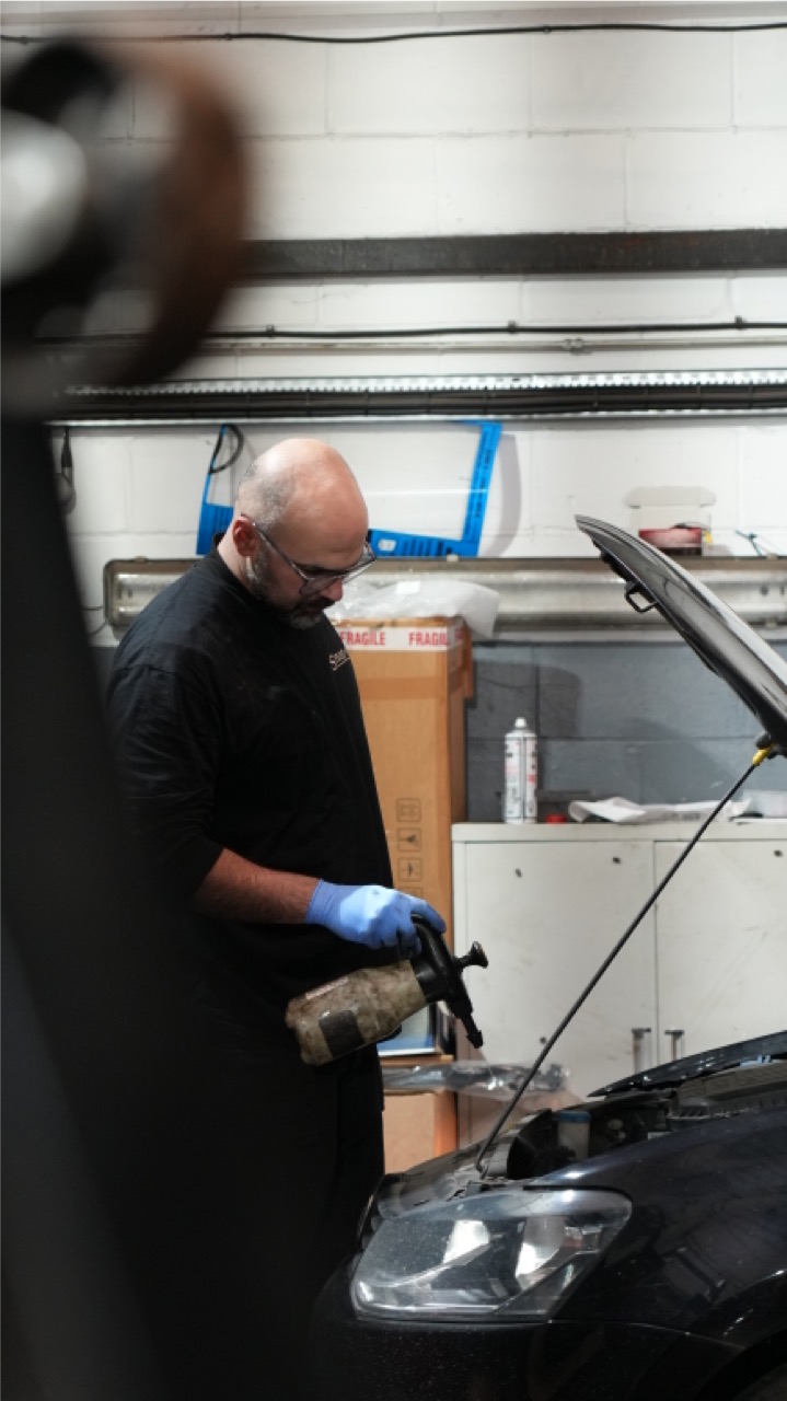 Technician topping up fluids under the bonnet at Motor Sense