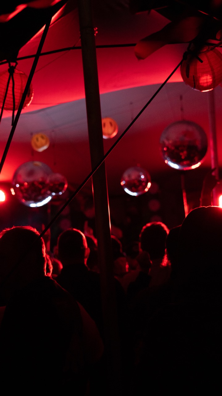 Crowd under disco balls in red light at Music Barn